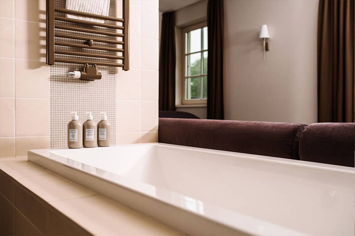 Freistehende Badewanne im offenen Bad mit Blick auf die Natur in der Deluxe Suite im Hotel Künstlerquartier Seezeichen.
