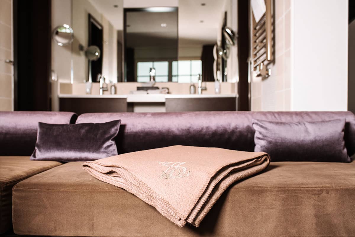 Luxuriöses Badezimmer mit Kissen und Handtuch auf einem samtigen Polster der Deluxe Suite im Hotel Künstlerquartier Seezeichen.