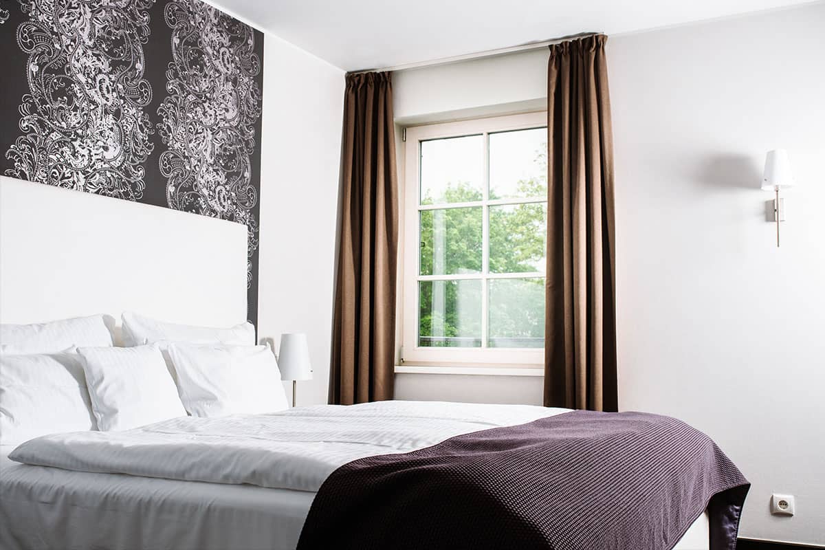 Schlafzimmer der Deluxe Suite im Hotel Künstlerquartier Seezeichen mit großem Doppelbett und Wandekoration.