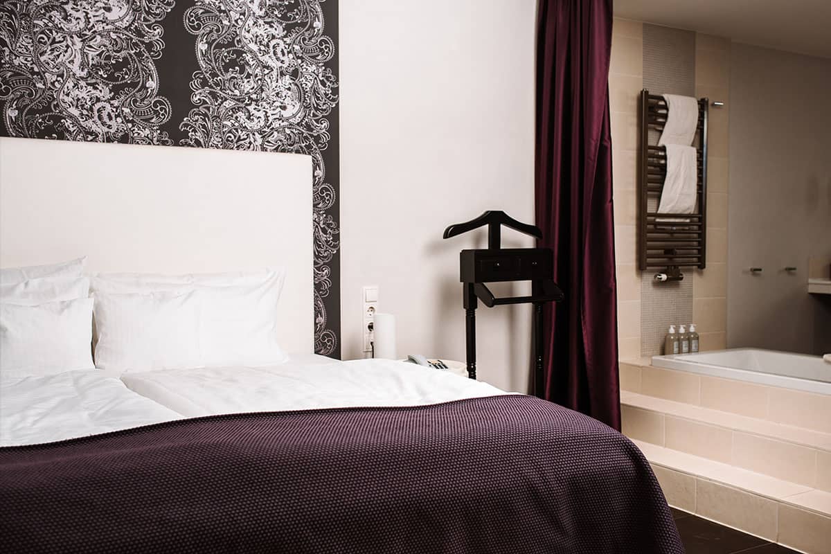 Luxuriöser Schlafbereich mit Durchgang zum Badezimmer mit Badewanne der Deluxe Suite im Hotel Künstlerquartier Seezeichen.