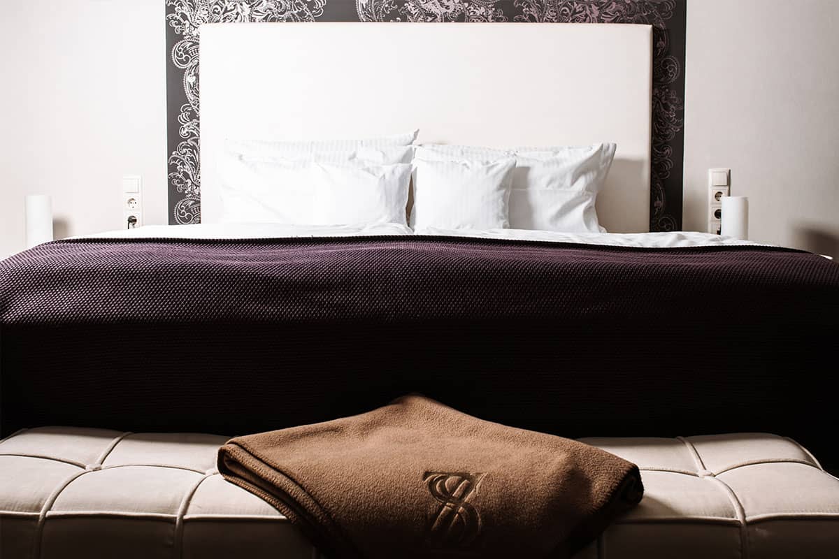 Hochwertiges Bett mit gepolstertem Kopfteil der Deluxe Suite im Hotel Künstlerquartier Seezeichen an der Ostsee.