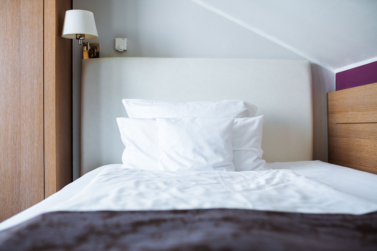 Einladendes Bett im Einzelzimmer des Hotel Künstlerquartier Seezeichen mit weichen Kissen.