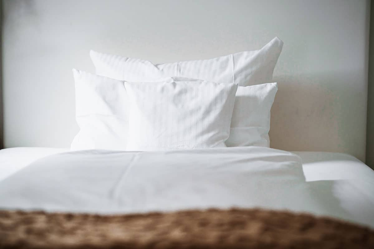 Modernes Einzelbett im Einzelzimmer des Hotel Künstlerquartier Seezeichen mit dekorativen Details.