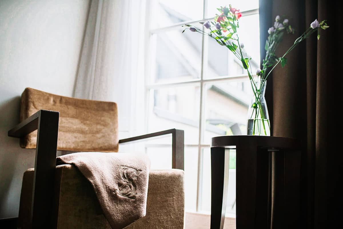 Einladender Stuhl mit dekorativer Decke und Beistelltisch im hellen Einzelzimmer des Hotel Künstlerquartier Seezeichen.