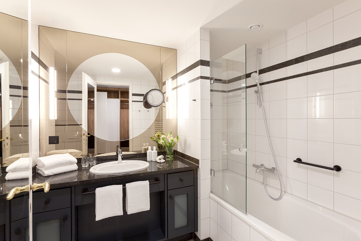 Badezimmer mit eleganter Badewanne, beleuchtetem Spiegel und hochwertiger Ausstattung im Studio des Vju Hotels.