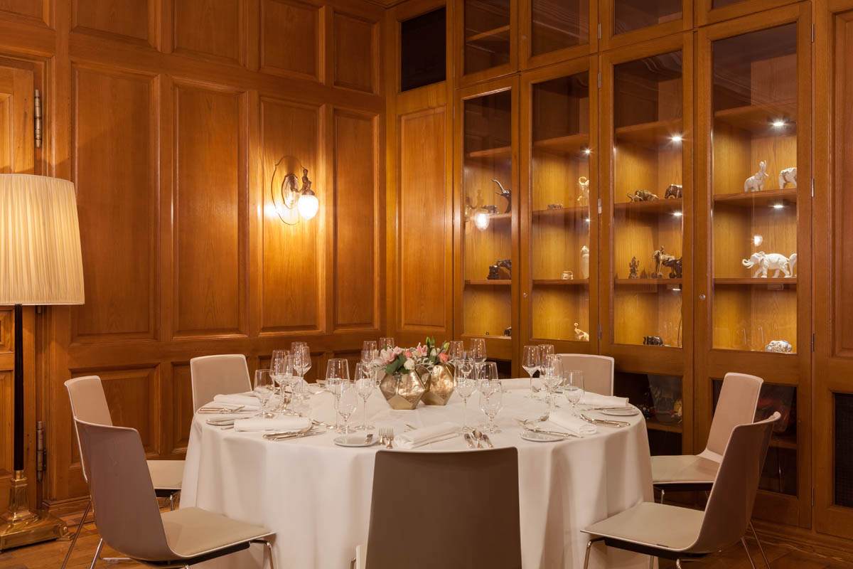Gedeckter Tisch im privaten Speiseraum des Hotel Elephant Weimar umgeben von Holztäfelung und dekorativen Vitrinen.
